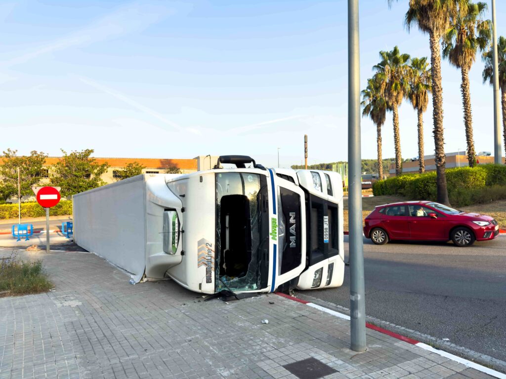 Overturned delivery truck lying on its side after a traffic accident on a city street.