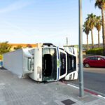 Overturned delivery truck lying on its side after a traffic accident on a city street.